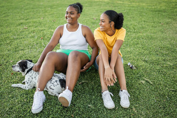 friends sitting on the grass in a park with their dog