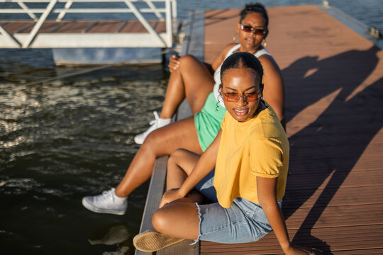 young black female friends sitting on a jetty