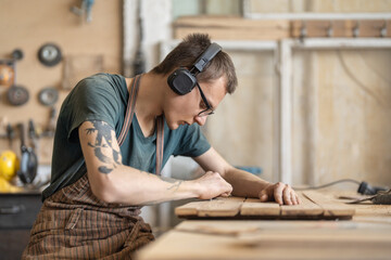 Young man in black headphones using grinder removes paint from f