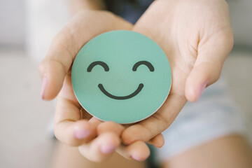 Hands holding green happy smile face paper cut, good feedback rating,think positive, customer review, assessment, child wellness,world mental health day, Compliment Day - obrazy, fototapety, plakaty