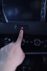 Finger pressing the emergency light button in the car indicates danger. Alarm button in the car. red triangle