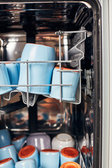 The process of washing yogrut jars in the dishwasher. Homemade yogurt making. Vertical photo.