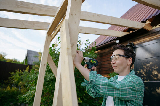 Female carpenter at work with a screwdriver in the backyard