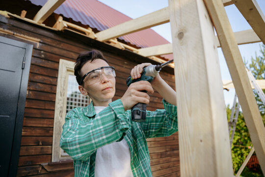 Female carpenter at work with a screwdriver in the backyard