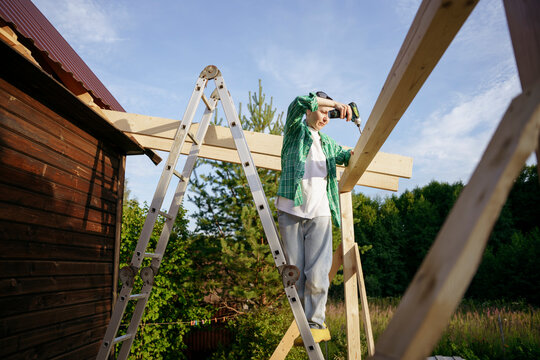Female carpenter at work with a screwdriver in the backyard