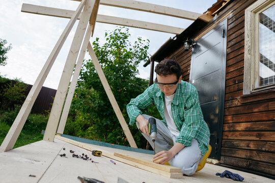 Female carpenter at work with a screwdriver in the backyard