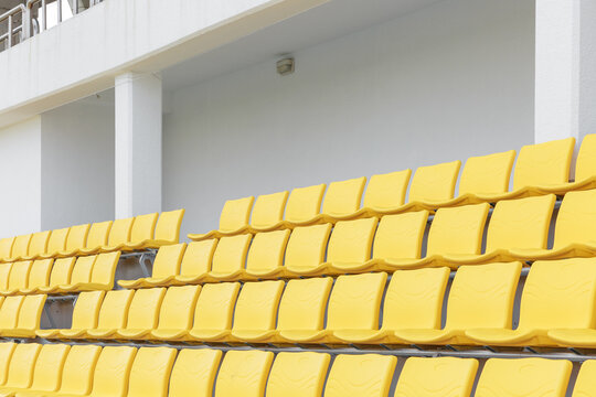 There are several empty yellow chairs in the stadium.