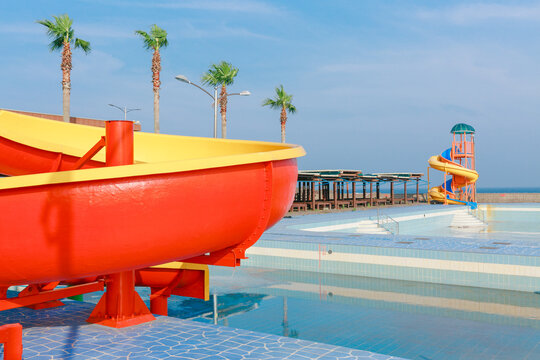 An empty pool and colorful slide by the beach.