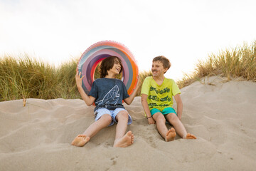 Funny kids at the beach dunes with float tube