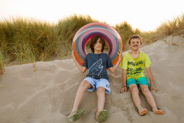 Funny kids at the beach dunes with float tube