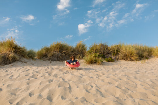 Funny boy enjoying by dunes with an float