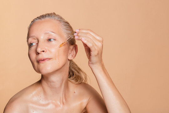 Middle age woman using serum for skin