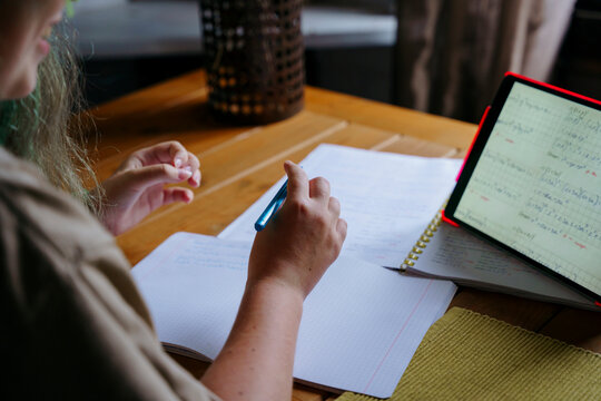 teen girl's hands doing homework using electronic tablet
