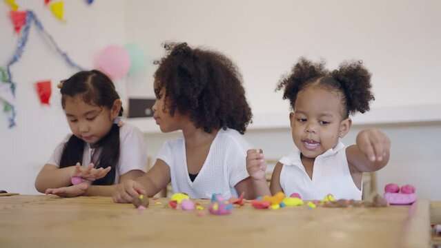 Group little asian and african american kids learning playing together sculpting plasticine create different shapes. Activity at home, pastime craft and hobby concept.