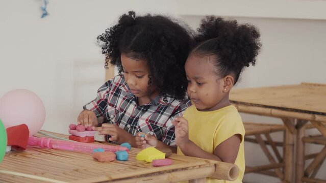 Two little african american  kids learning playing together sculpting plasticine create different shapes. Activity at home, pastime craft and hobby concept.