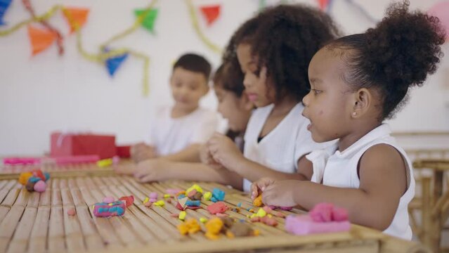 Group little asian and african american kids learning playing together sculpting plasticine create different shapes. Activity at home, pastime craft and hobby concept.
