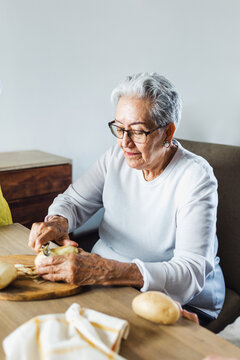 Hispanic Grandmother Peeling Potatoes And Cooking At Home In Mexico Latin America