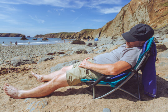 Man asleep in a chair on a beach.