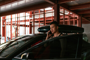 man talking on cell phone beside the car