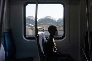 Profile of boy in mask alone on train
