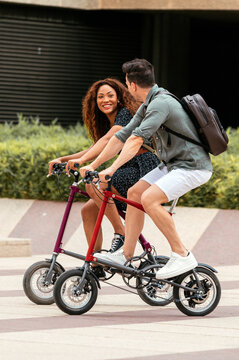 Diverse couple riding folding bikes in park