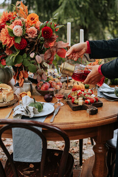 Anonymous female sets dining table in autumn garden.