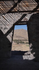 Photo prise à l'intérieur d'une petite maison en ruine et vers une porte, sur le flanc d'une haute montagne péruvienne, en plein jour