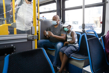 Father and son watch phone on city bus