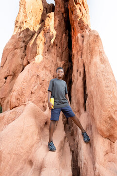 boy poses on red rock formation