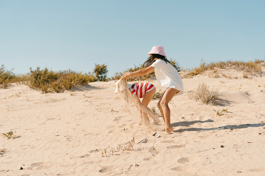 Girls playing with the sand by dunes