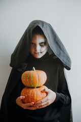Scary boy holds pumpkins for halloween celebration