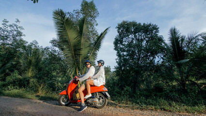 Love couple on red motorbike in white clothes to go on forest road trail trip. Two caucasian...