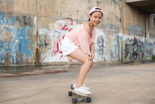 Teenager girl, Beautiful happy Asian healthy woman smiling, riding and playing extreme sports skateboard as outdoor activity with happiness, relaxation during holidays in summer vacation.