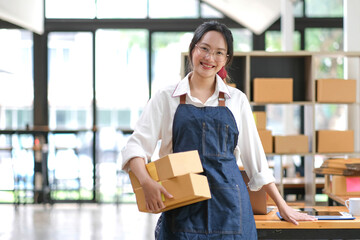 Portrait of Asian young woman working with a box at home the workplace.start-up small business owner, small business entrepreneur SME or freelance business online and delivery concept.