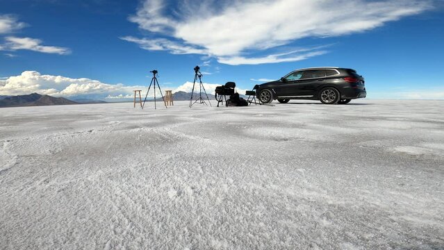 static shot of video equipment set up for an interview waiting for interviewee and interviewer. two camera, two chairs, one black car at bonnesville salt flats utah 4k epic shot