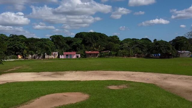 a baseball field in a rural zone of the dominican republic. a dolly shot
