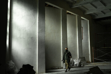 Man stands in an abandoned building. wandering men. man in a protective cloak with a hood. Post apocalypse. traveling in a post-apocalyptic world.
