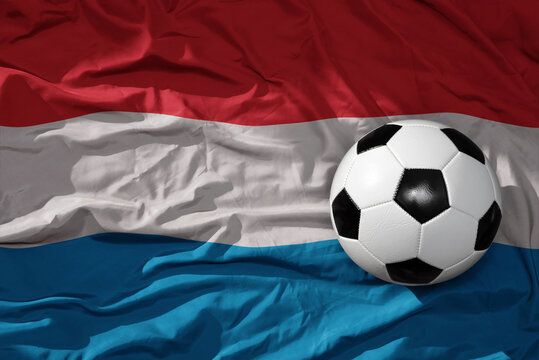 vintage football ball on the waveing national flag of luxembourg background. 3D illustration