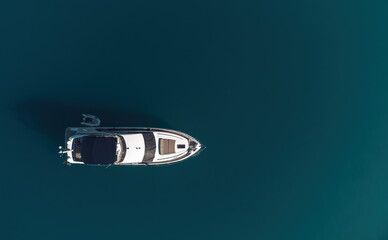 Aerial yacht on calm sea. Luxury cruise trip. View from above of white boat on deep blue water. Aerial view of rich yacht sailing sea. Summer journey on luxury ship.