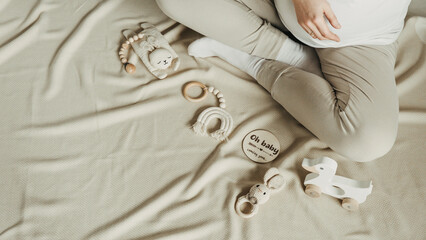 Baby shower, infant care concept. Pregnant woman holding wooden newborn stuff, baby accessories -...