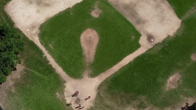 a Boom shot of a baseball field in the dominican republic with kids playing in the home base
