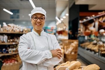 Portrait of confident female baker working in supermarket bakery and looking at camera.