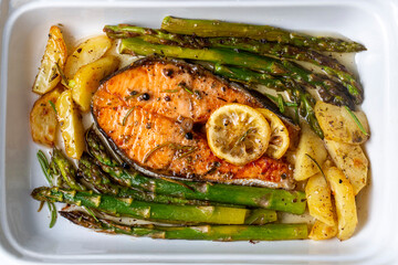Grilled, baked salmon served on a plate with asparagus and potatoes.