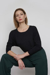 Fototapeta premium Serie of studio photos of young female model wearing simple comfortable outfit, organic cotton blouse and green trousers
