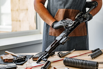 Close up of a man in apron wiping his firearm with a cloth