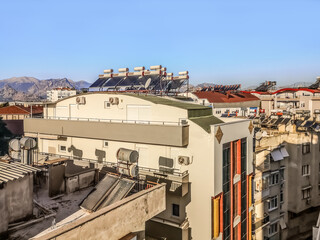 Roofs of residential buildings with solar panels and water tanks in Antalya, Turkey. Alternative energy sources in the urban area