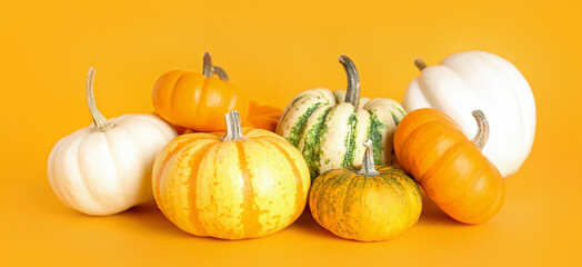 Heap of different pumpkins on orange background