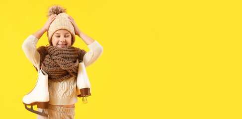 Cute little girl in winter clothes and with ice skates on yellow background with space for text