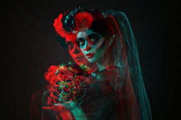 Young woman with painted skull on her face for Mexico's Day of the Dead (El Dia de Muertos) against black background