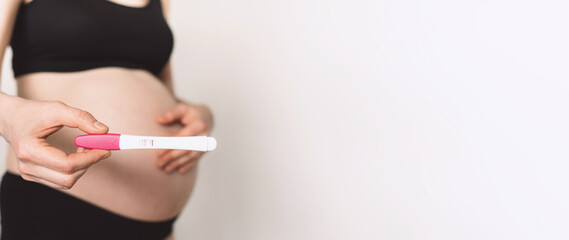 Pregnant woman showing positive pregnancy test on white background. Copy space. Banner - obrazy, fototapety, plakaty